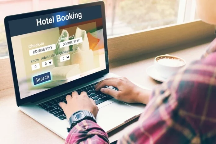 Man booking hotel room while using laptop