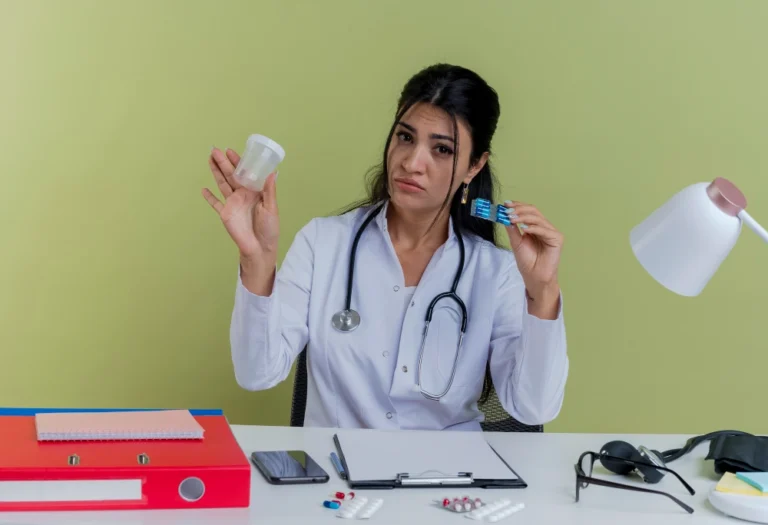 female doctor wearing medical robe and stethoscope sitting at desk