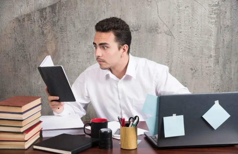 man looking closely at notebook at the desk