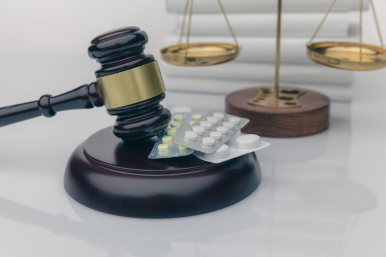 Drugs and law, Judge gavel and colorful pills on a wooden desk