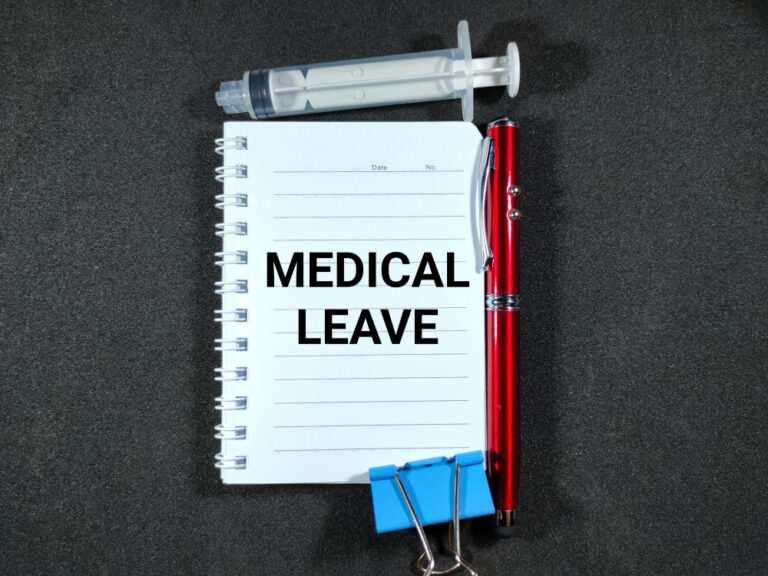 MEDICAL LEAVE on notebook with syringe and pen