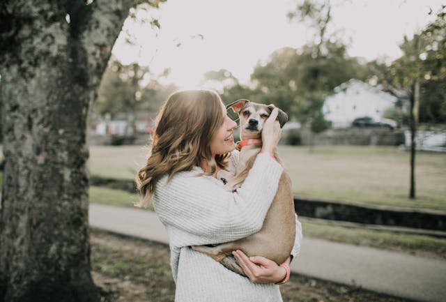 Smiling Woman Carrying Dog