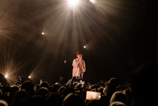 Man in White Dress Shirt Singing on Stage